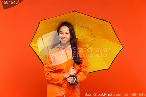 Image of The young girl posing at studio in autumn jacket isolated on red