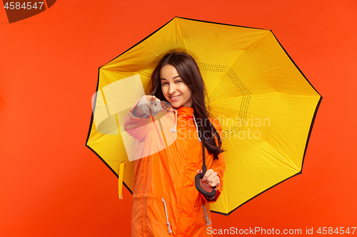 Image of The young girl posing at studio in autumn jacket isolated on red