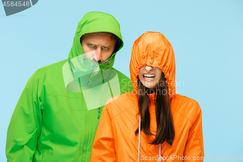 Image of The young couplel posing at studio in autumn jackets isolated on blue