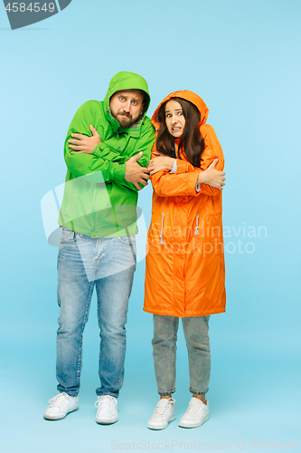 Image of The young couplel posing at studio in autumn jackets isolated on blue