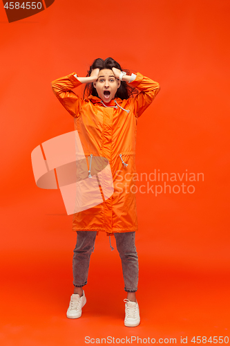 Image of The young girl posing at studio in autumn jacket isolated on red