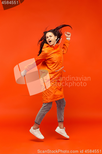 Image of The young girl posing at studio in autumn jacket isolated on red