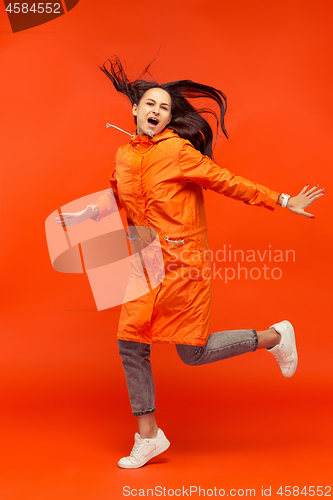 Image of The young girl posing at studio in autumn jacket isolated on red