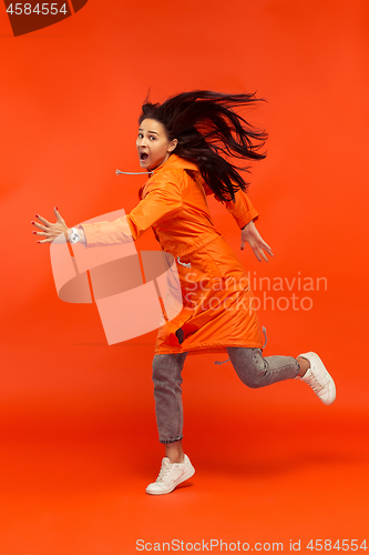 Image of The young girl posing at studio in autumn jacket isolated on red