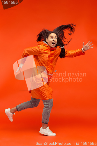 Image of The young girl posing at studio in autumn jacket isolated on red