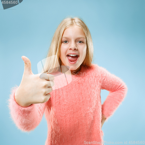 Image of The happy teen girl standing and smiling against blue background.