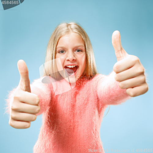 Image of The happy teen girl standing and smiling against blue background.