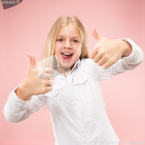 Image of The happy teen girl standing and smiling against pink background.