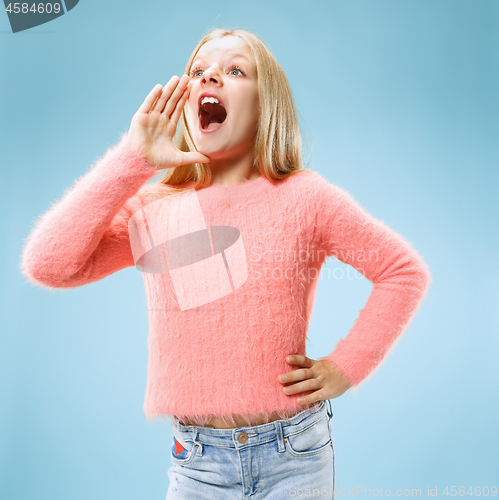 Image of Isolated on blue young casual teen girl shouting at studio