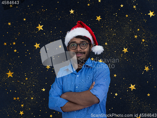 Image of Indian man wearing traditional Santa Claus hat with stars in bac