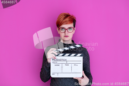 Image of woman holding movie clapper isolated on pink background