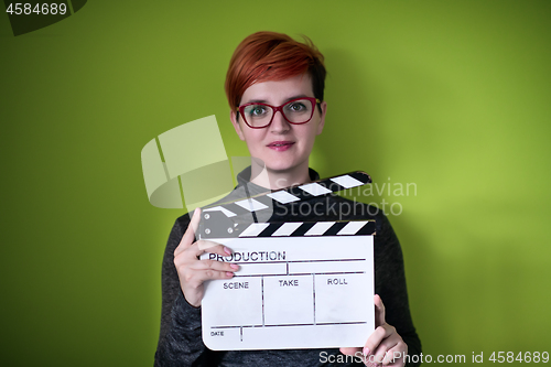 Image of woman holding movie clapper against green background