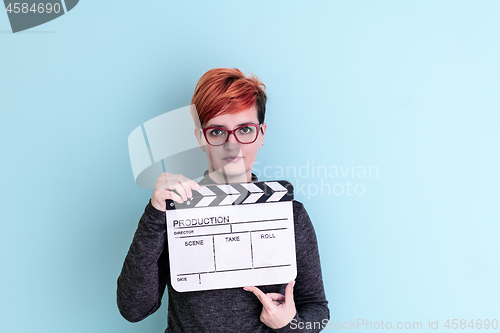 Image of woman holding movie clapper against cyan background