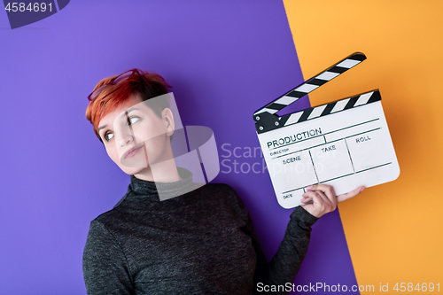 Image of woman holding movie clapper against colorful background