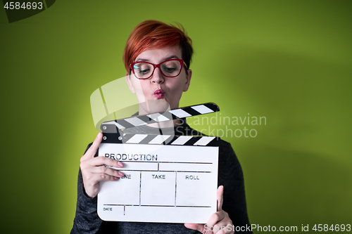 Image of woman holding movie clapper against green background