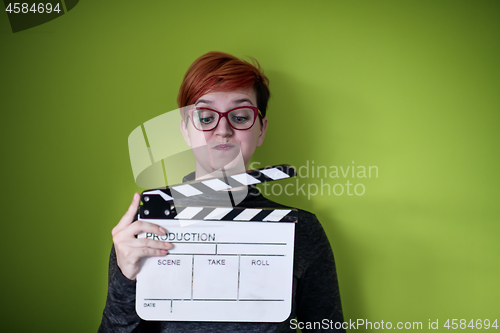 Image of woman holding movie clapper against green background