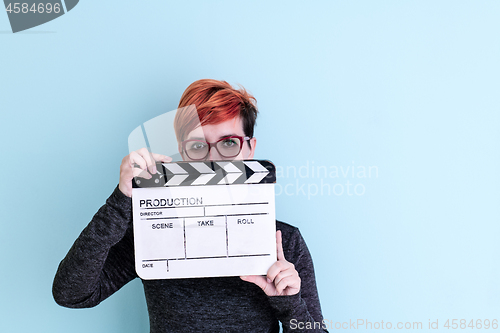 Image of woman holding movie clapper against cyan background