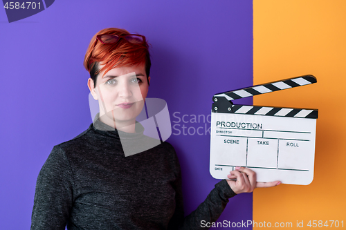 Image of woman holding movie clapper against colorful background