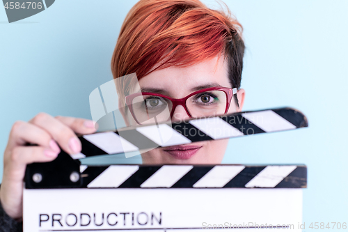 Image of woman holding movie clapper against cyan background