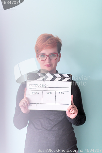 Image of woman holding movie clapper against cyan background