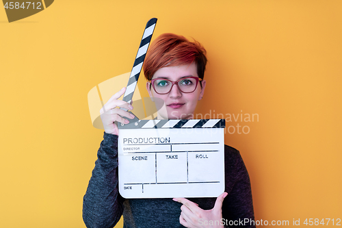 Image of woman holding movie clapper against yellow background