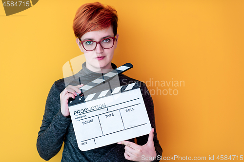 Image of woman holding movie clapper against yellow background