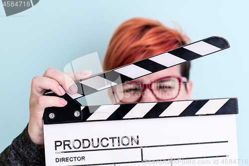 Image of woman holding movie clapper against cyan background