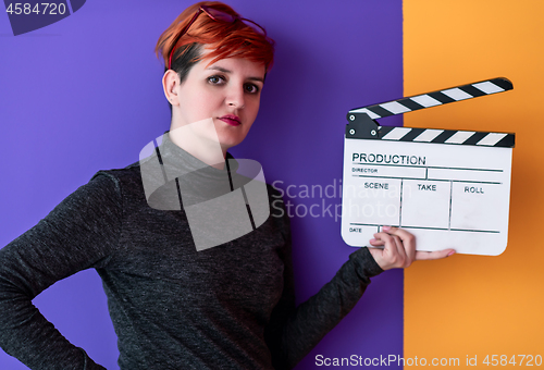 Image of woman holding movie clapper against colorful background