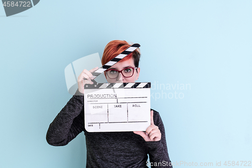 Image of woman holding movie clapper against cyan background