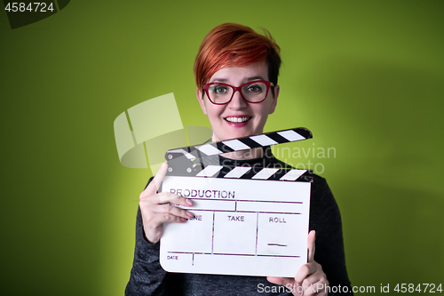 Image of woman holding movie clapper against green background