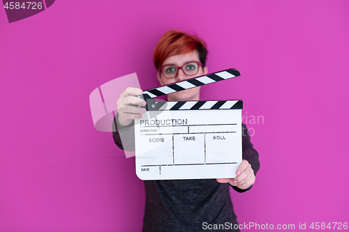 Image of woman holding movie clapper isolated on pink background