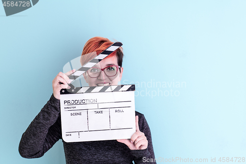 Image of woman holding movie clapper against cyan background