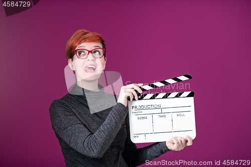 Image of woman holding movie clapper isolated on pink background