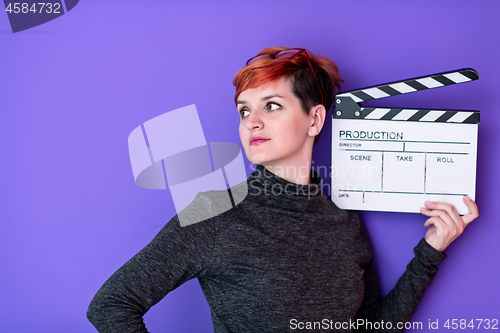 Image of woman holding movie clapper against purple background