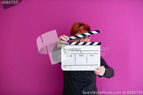 Image of woman holding movie clapper isolated on pink background