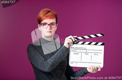 Image of woman holding movie clapper isolated on pink background