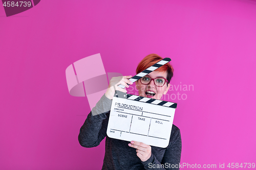 Image of woman holding movie clapper isolated on pink background