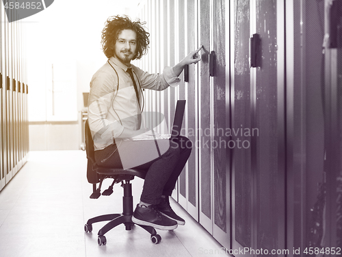 Image of engineer working on a laptop in server room