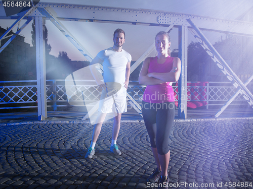 Image of portrait of couple jogging across the bridge in the city