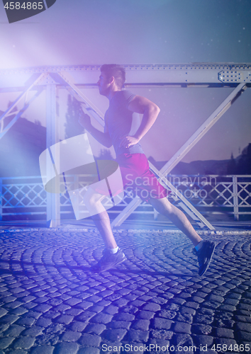 Image of man jogging across the bridge in the city