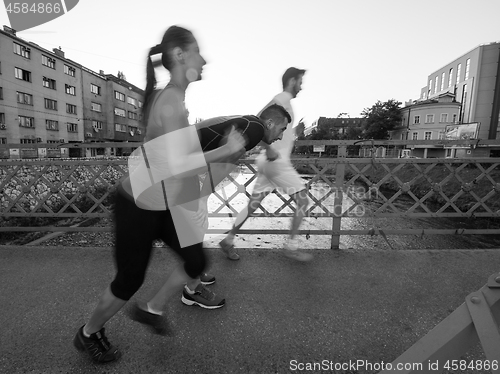 Image of young couple jogging across the bridge in the city