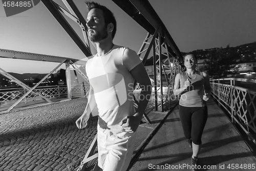 Image of couple jogging across the bridge in the city