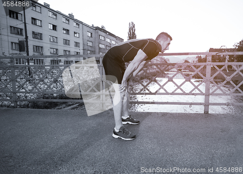 Image of man jogging across the bridge at sunny morning