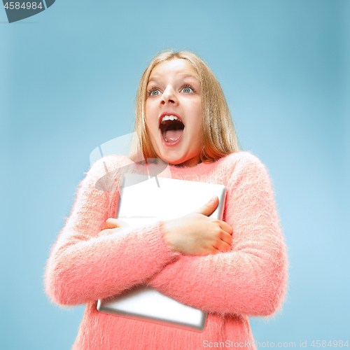 Image of Teen girl with laptop. Love to computer concept. Attractive female half-length front portrait, trendy blue studio backgroud.