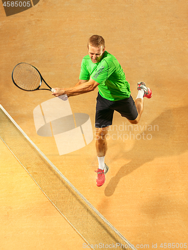 Image of The one jumping player, caucasian fit man, playing tennis on the earthen court