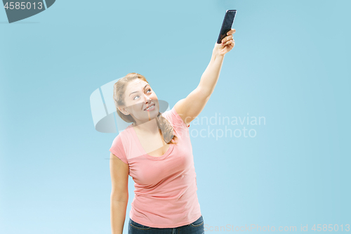 Image of Portrait of a happy smiling casual girl showing blank screen mobile phone isolated over blue background