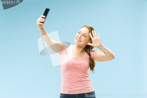 Image of Portrait of a happy smiling casual girl showing blank screen mobile phone isolated over blue background