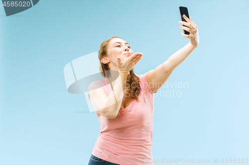 Image of Portrait of a happy smiling casual girl showing blank screen mobile phone isolated over blue background