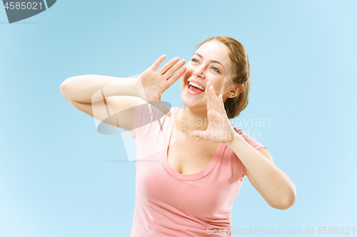 Image of Isolated on blue young casual woman shouting at studio