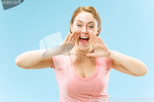 Image of Isolated on blue young casual woman shouting at studio